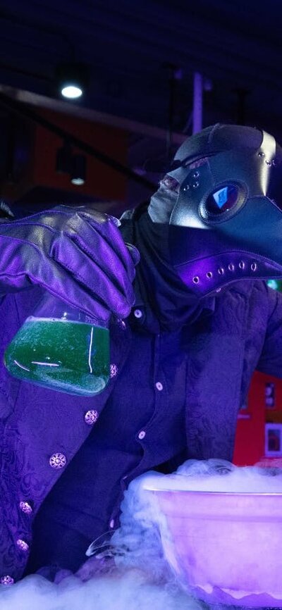 A person dressed in a Halloween Costume using liquid nitrogen in Questacon's QLab