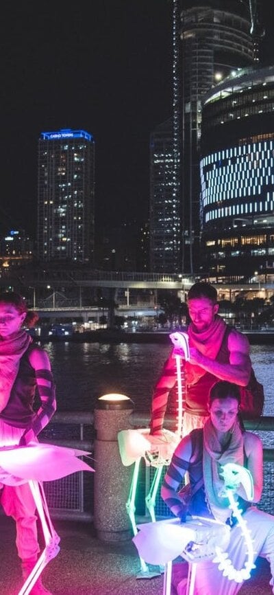 Puppeteers operate rainbow LED flamingo skeletons