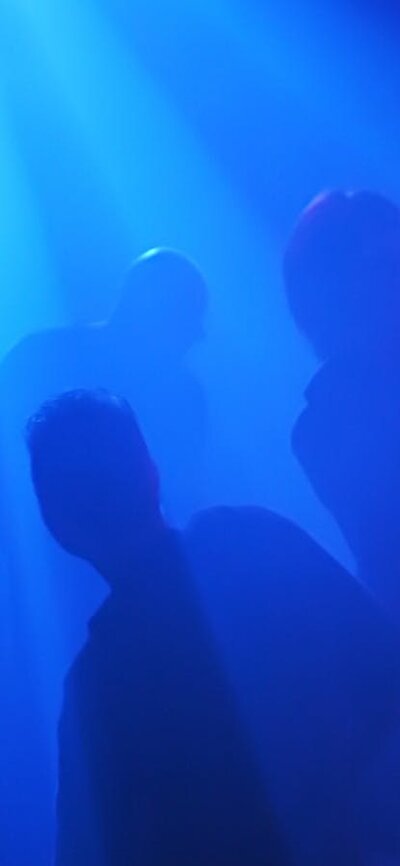 Blue image with shadows of people of what looks like a nightclub