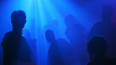 Blue image with shadows of people of what looks like a nightclub