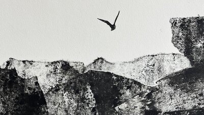 A printed artwork featuring a black landscape with a bird flying overhead