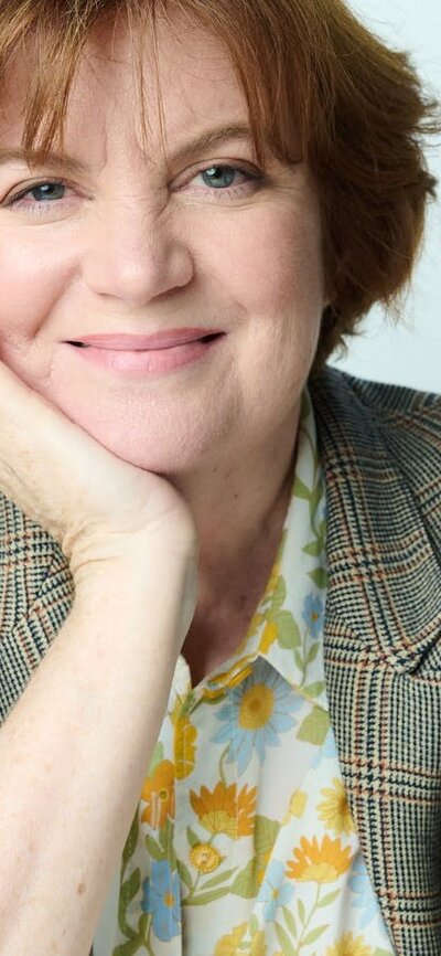 Woman smiles at camera leaning her chin on her hand