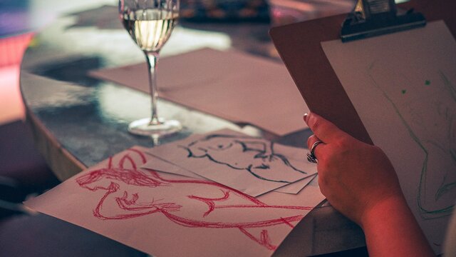 Drawing of naked humans next to a glass of wine