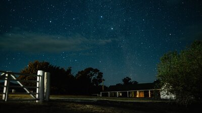 Lanyon Homestead under a starlit sky. White gate visible in foreground.