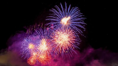 Fireworks bursting with purple and pink colours in in the night sky