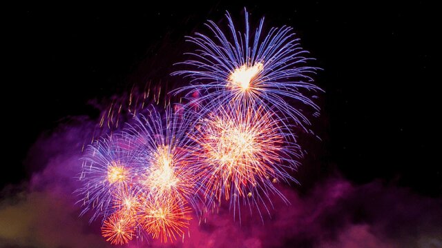 Fireworks bursting with purple and pink colours in in the night sky