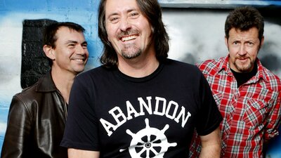 The three members of Things of Stone and Wood, casually dressed and smiling happily.