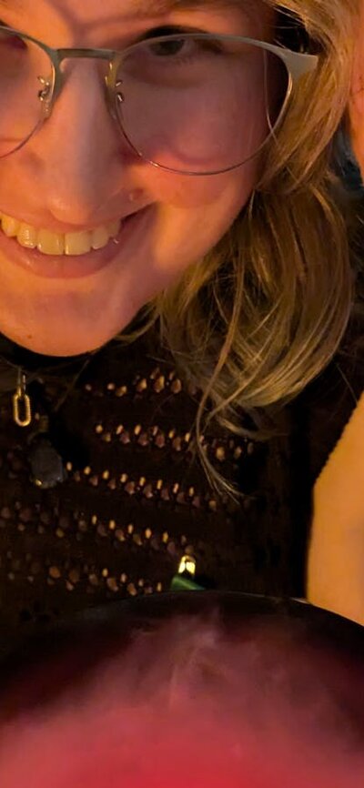Two women smiling over a cauldron of red, steamy brew