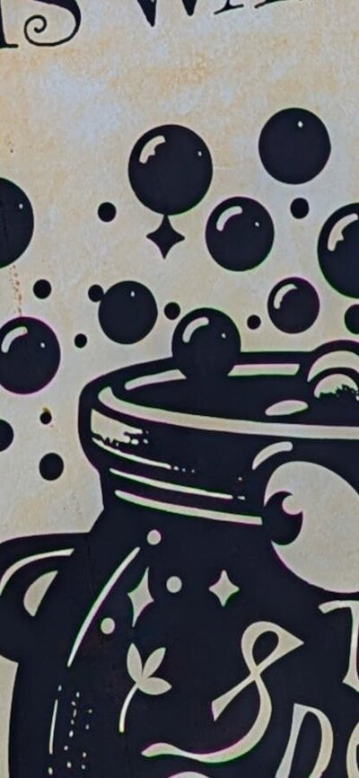 Sign pointing the way to The Sneaky Cauldron with a logo