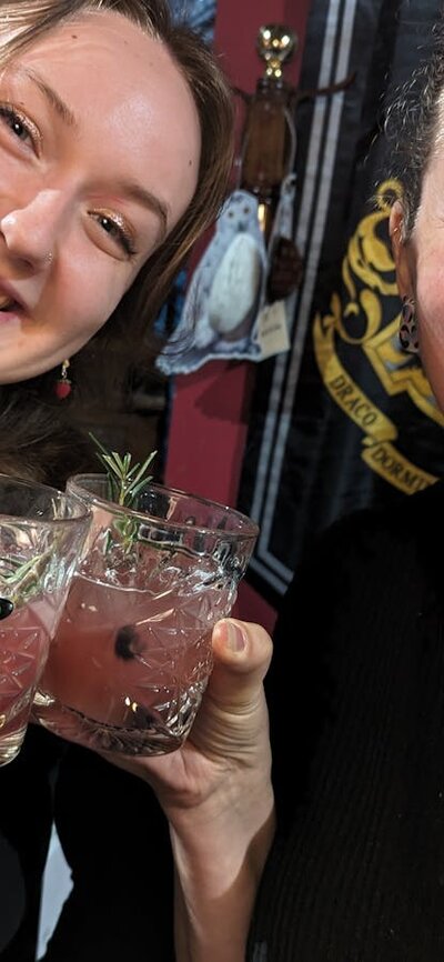 Two women smiling and drinking cocktails they brewed themselves.
