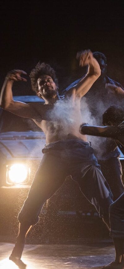 SPEAR (2015) Group of men dancing expressively with headlights on behind them