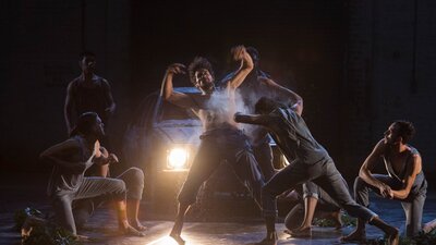 Group of men dancing expressively with headlights on behind them