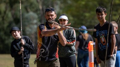 Spear Throwing Man throwing spear with kids in background