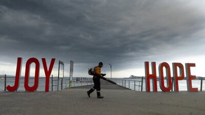 Red large words saying joy and hope on a beach front with a man walking in between