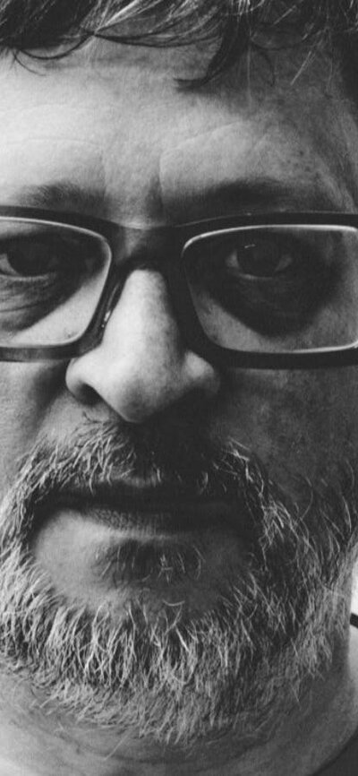 Black and white image of man wearing glasses looking at camera