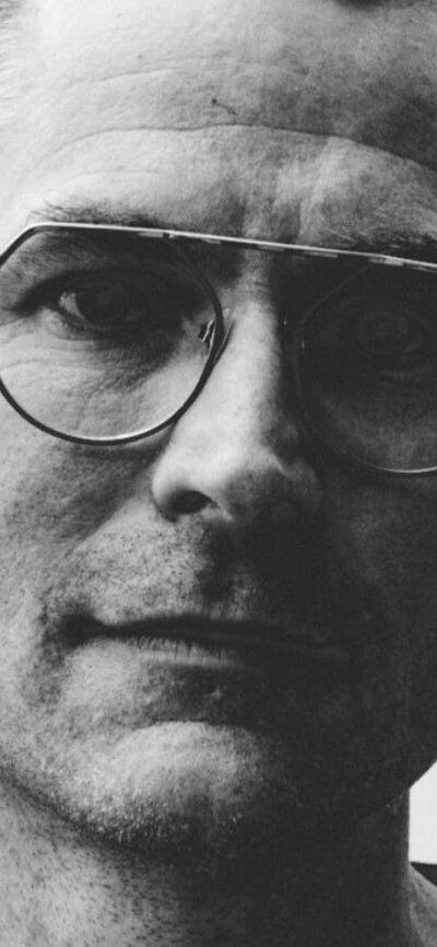 Black and white image of man wearing glasses looking at camera
