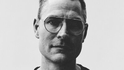 Black and white image of man wearing glasses looking at camera