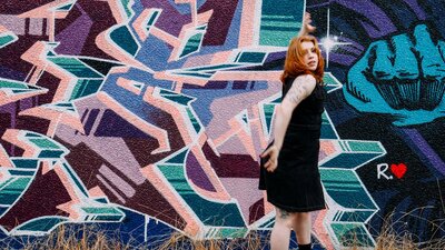 SPHERE marks 10 years of Australian Dance Party A figure is paused mid-motion on the right. The wall to her left is a mural of angular shapes