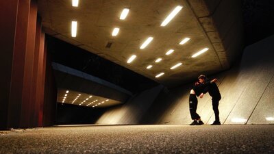 SPHERE will be an immersive dance and film experience On the left is a large concrete underpass, lit up at night. Two small figures are locked together
