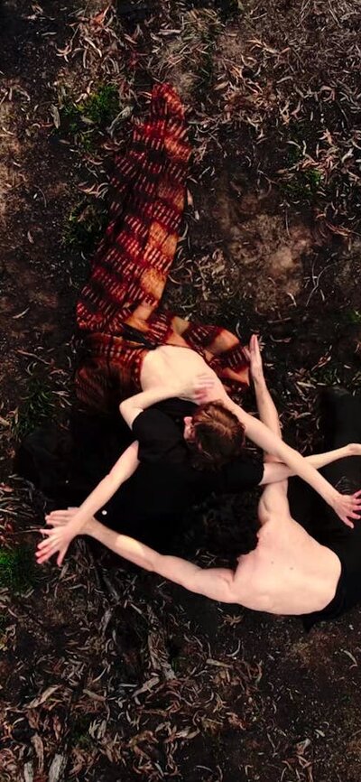 Immerse yourself in live dance and film with SPHERE Bird's eye view of 3 figures interlocked together. They're surrounded by the dirt of a forest floor.