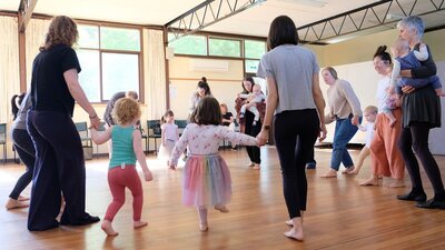 A group of children and their parents participate in a dance workshop