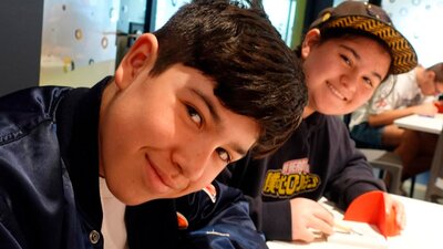 Two teen boys smiling at camera while doing a creative activity