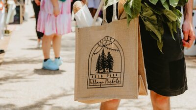 A peson holding a hessian Haig Park Village Market bag filled with bread and produce