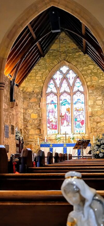 Stained glass windows, wooden pews and memorial plaques inside an old sandstone church