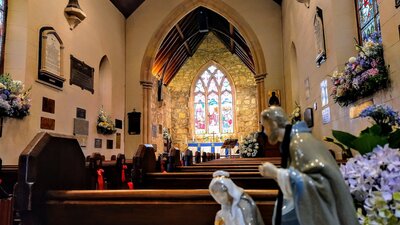Stained glass windows, wooden pews and memorial plaques inside an old sandstone church