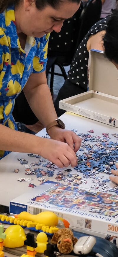 Two women in duck outfits complete a puzzle