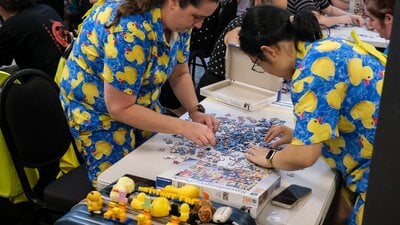 Two women in duck outfits complete a puzzle