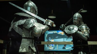 Two armoured men size each other up with their swords ready