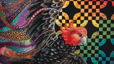 Freedom quilt by Helen Godden of a gang-gang cockatoo in flight with bright details surrounding