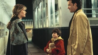 A man and a woman stand facing each other with a young boy between them