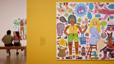 Gallery 8 featuring Kaylene Whiskey’s Flying to New York 2022 (detail) © Roslyn Oxley9 Gallery Two young people view a portrait, and in the foreground, a colourful portrait hangs on a yellow wall