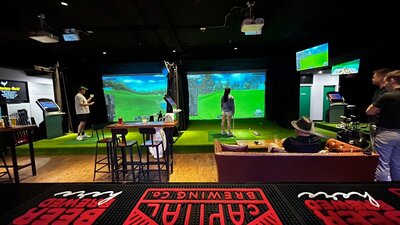 Guests playing at Status Golf Guests playing indoor golf at Status Golf