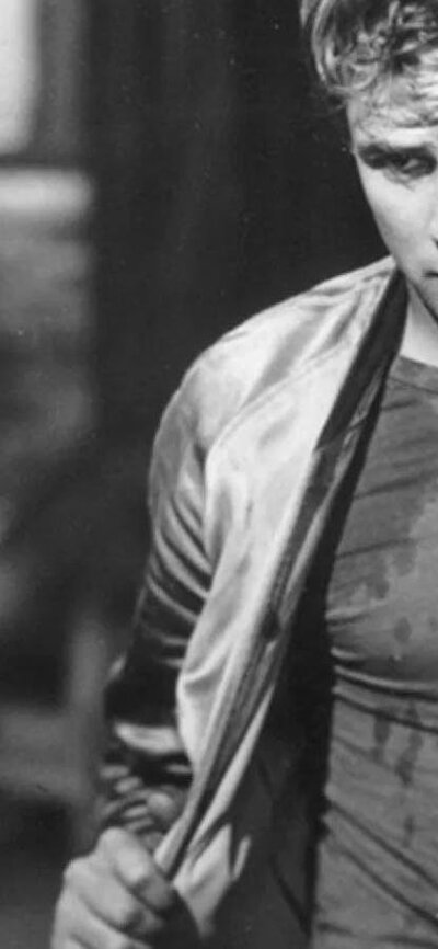 Black and white image of man taking off his jacket walking past woman staring at him