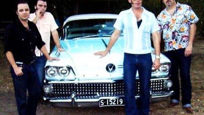 Photo of group of four men around 1950s classic car.