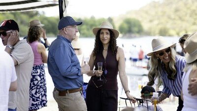 Spectators with drinks standing by the lake watching the racing