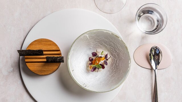 ALLTA restaurant Fine dining Korean dish displayed on a white plate with a bowl on top.