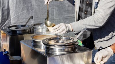 Image of hands ladling soup into a takeaway cup