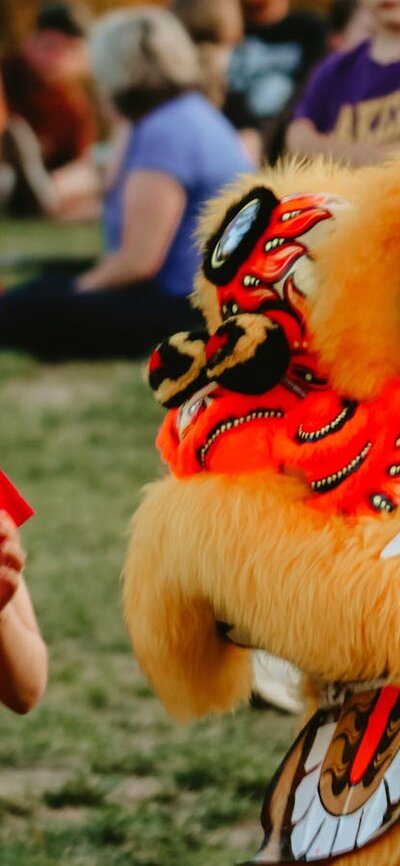 Image of a dragon dancer greeting a man and baby