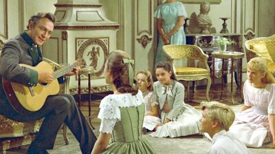Man sitting in lush interior playing guitar to children sitting on floor