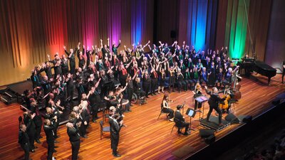 choir members and orchestra on stage performing