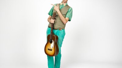 AsparaGus the guitarist wearing blue pants and green hair