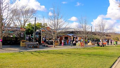 A landscape image shows a row of food vans and vendor stalls with lots of people of all ages