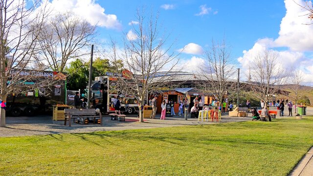 A landscape image shows a row of food vans and vendor stalls with lots of people of all ages