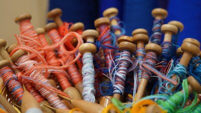 A close-up image of red and blue yarn on weaving bobbins