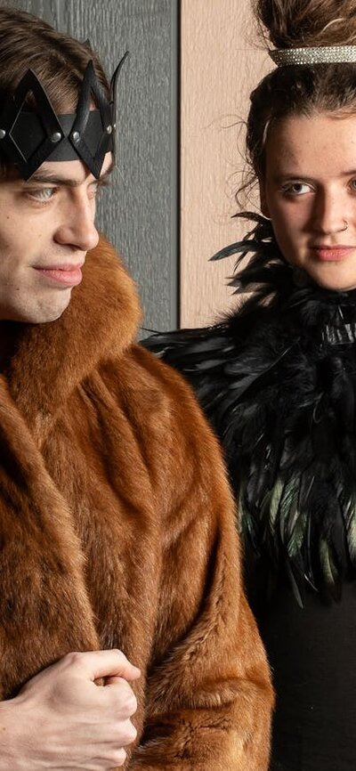 Winter's Tale Queen looking at King, King looking off to the distance, both in furs and feathers