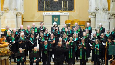 Choir singing on the altar steps, with Dan Walker conducting and Lindy Reksten, cello, at choir left